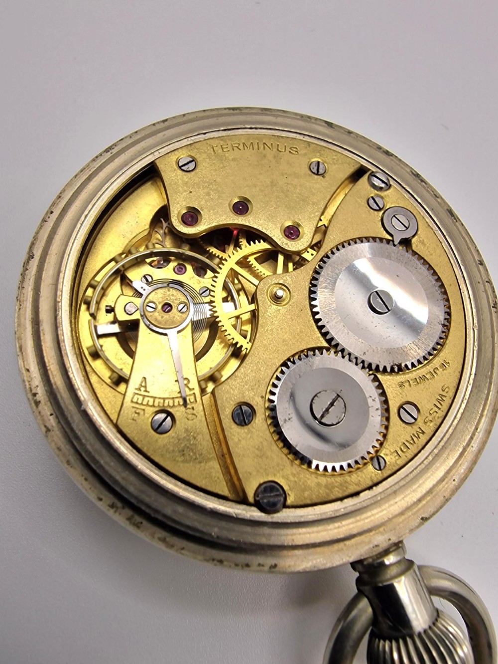 An open-face vintage Terminus military pocket watch featuring a white enamel dial with bold black Arabic numerals, a sub-seconds subdial at six oclock, and a reeded bezel. View IV