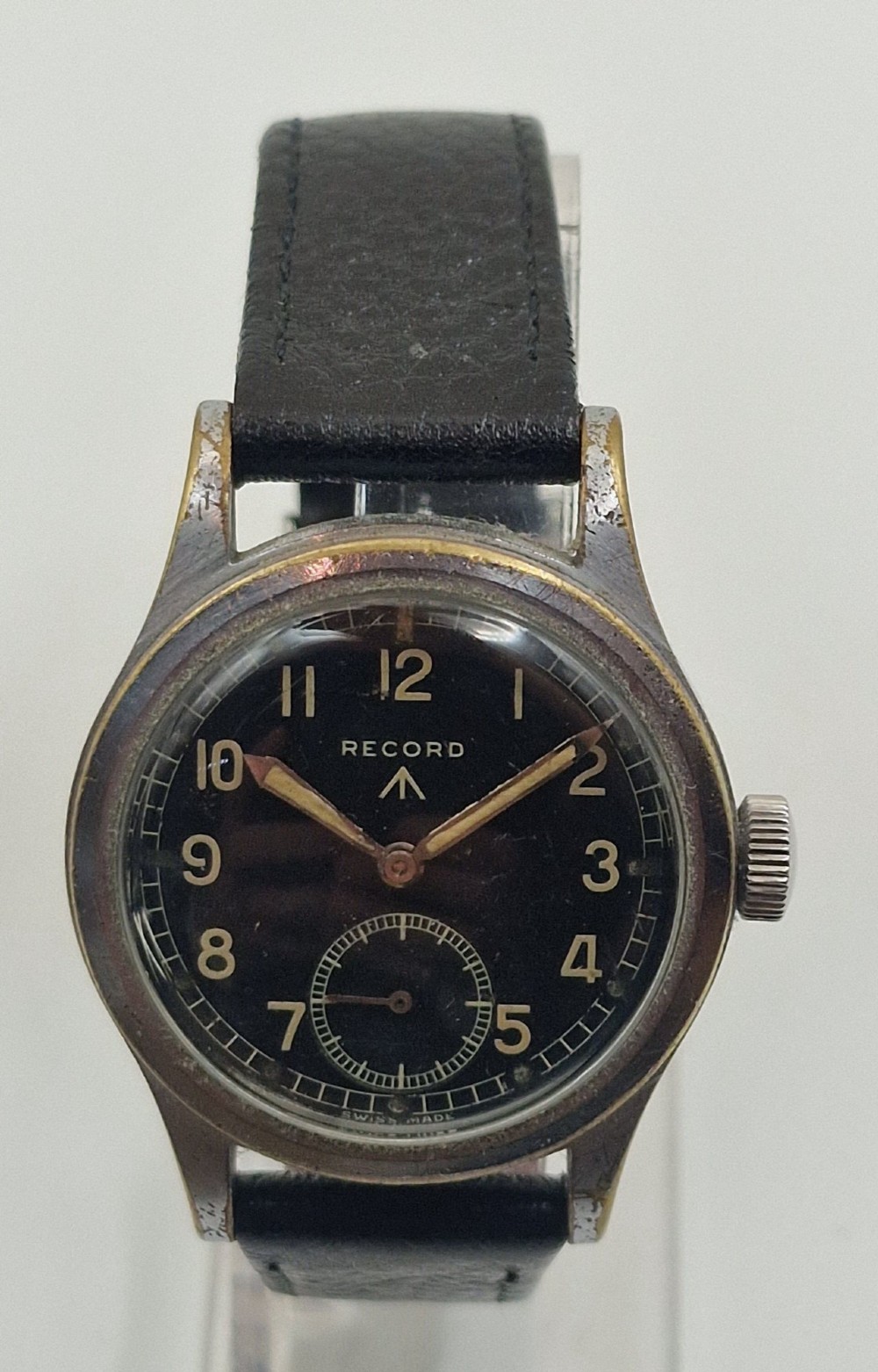 A 1940s Record military wristwatch featuring a black dial with luminous numerals, broad arrow mark, sub-seconds dial, and a black leather strap.