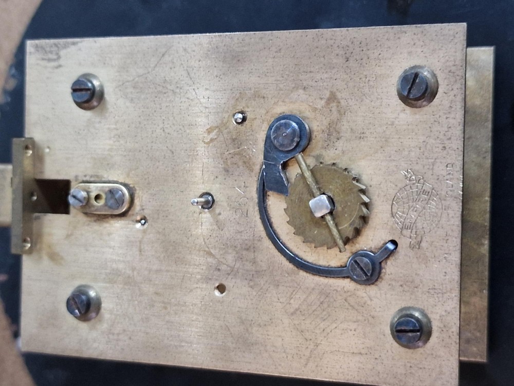 A circular brass Smiths Astral ships bulkhead clock with a white face, black Roman numerals, and a red second hand. View V