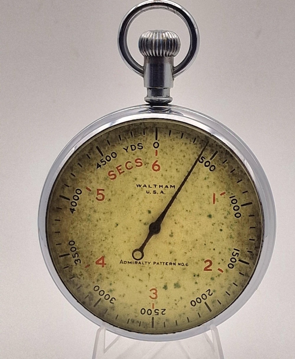 A circular vintage Waltham Admiralty Pattern No. 6 naval pocket timer featuring a chrome-plated metal casing and an aged cream dial with black and red markings.