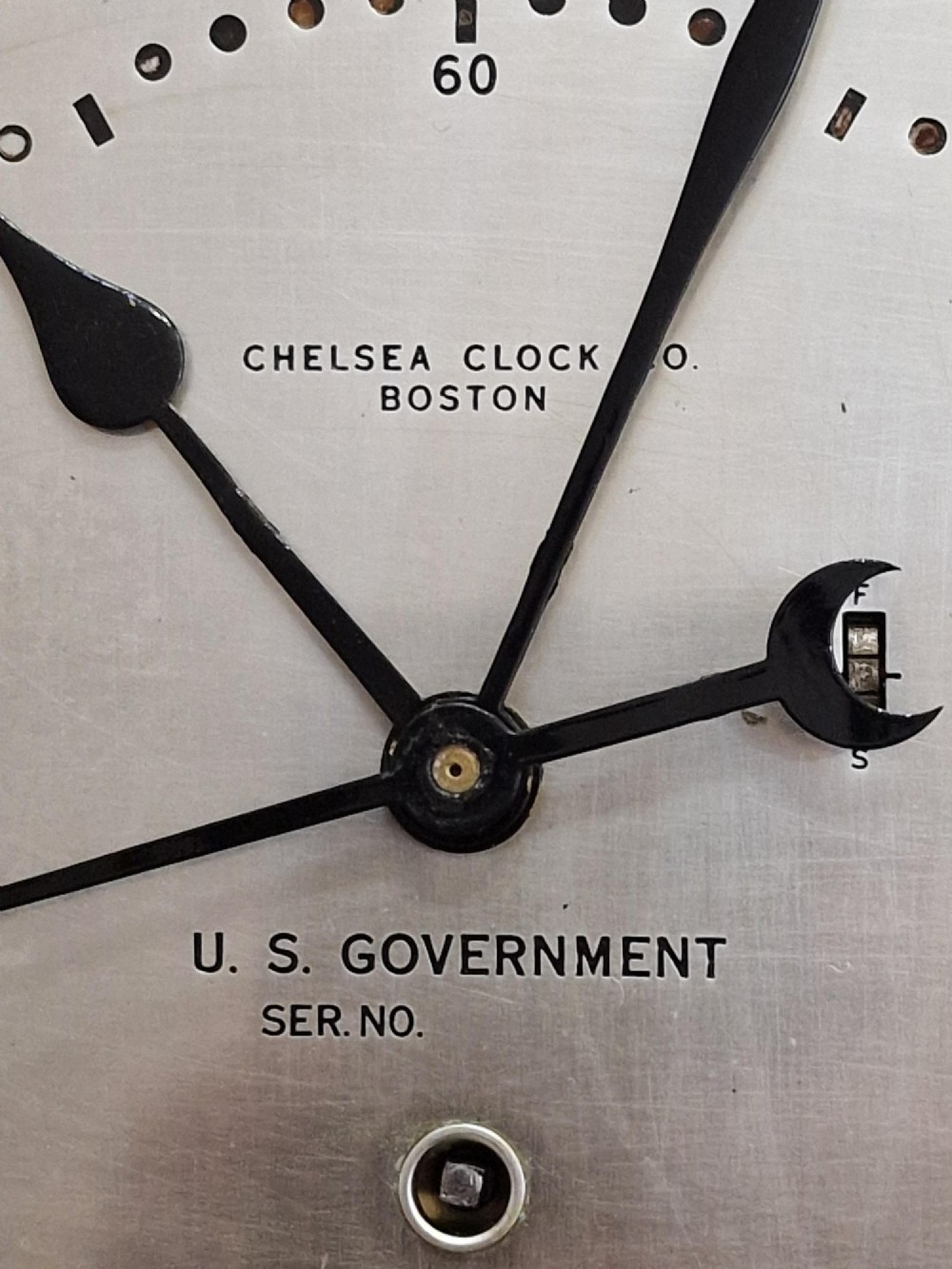 A circular black maritime wall clock featuring a twenty-four-hour dial face marked U.S. Government and Chelsea Clock Co. Boston. View II