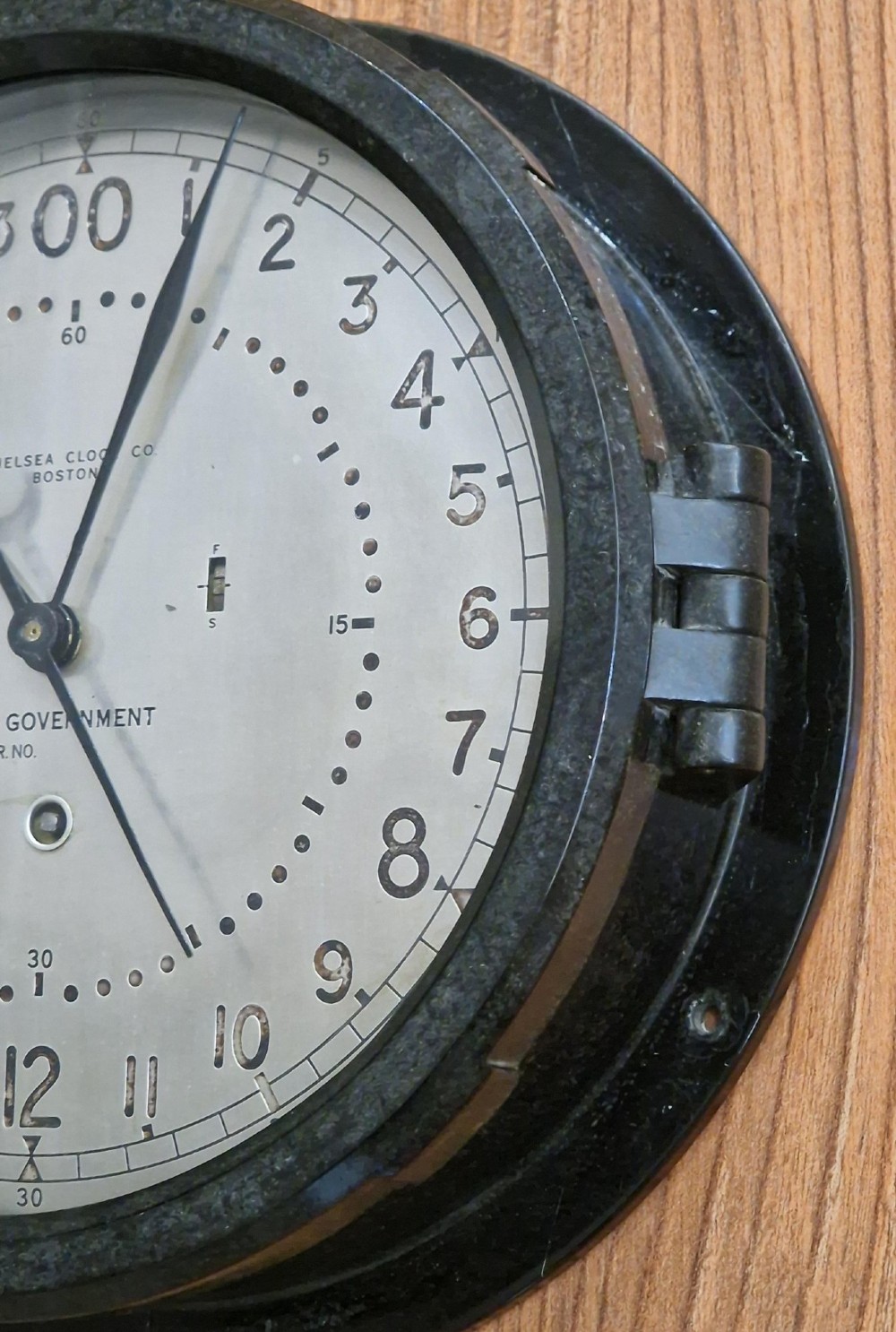 A circular black maritime wall clock featuring a twenty-four-hour dial face marked U.S. Government and Chelsea Clock Co. Boston. View V