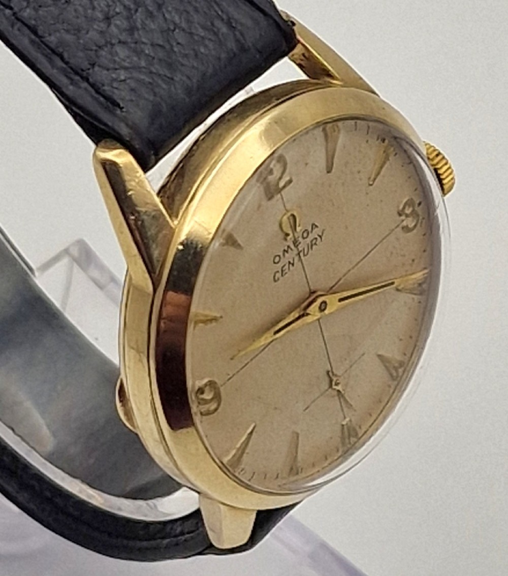 A 1954 Omega Century wristwatch with a gold-filled circular case, patinated dial with arrow markers, sub-seconds display, and a black leather strap. View VII