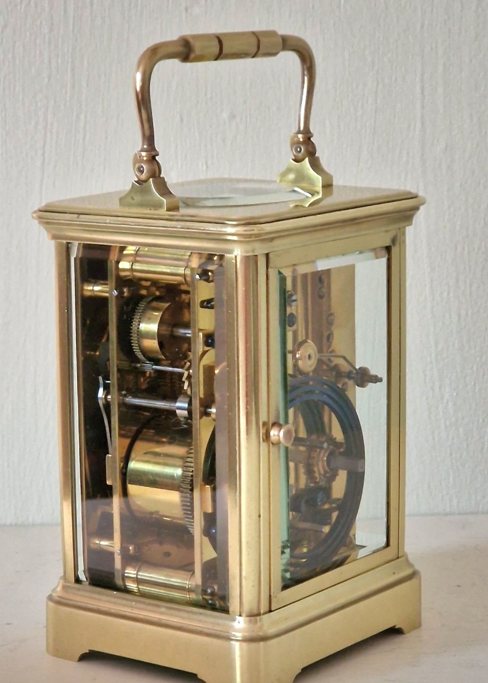 A French brass carriage clock with a top carrying handle, white enamel dial with Roman numerals, and clear glass side panels. View III
