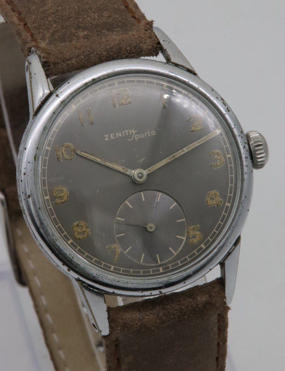 A 1950s Zenith Sporto mechanical wristwatch featuring a grey dial, Arabic numeral hour markers, a sub-seconds dial, and a brown leather strap. View IV