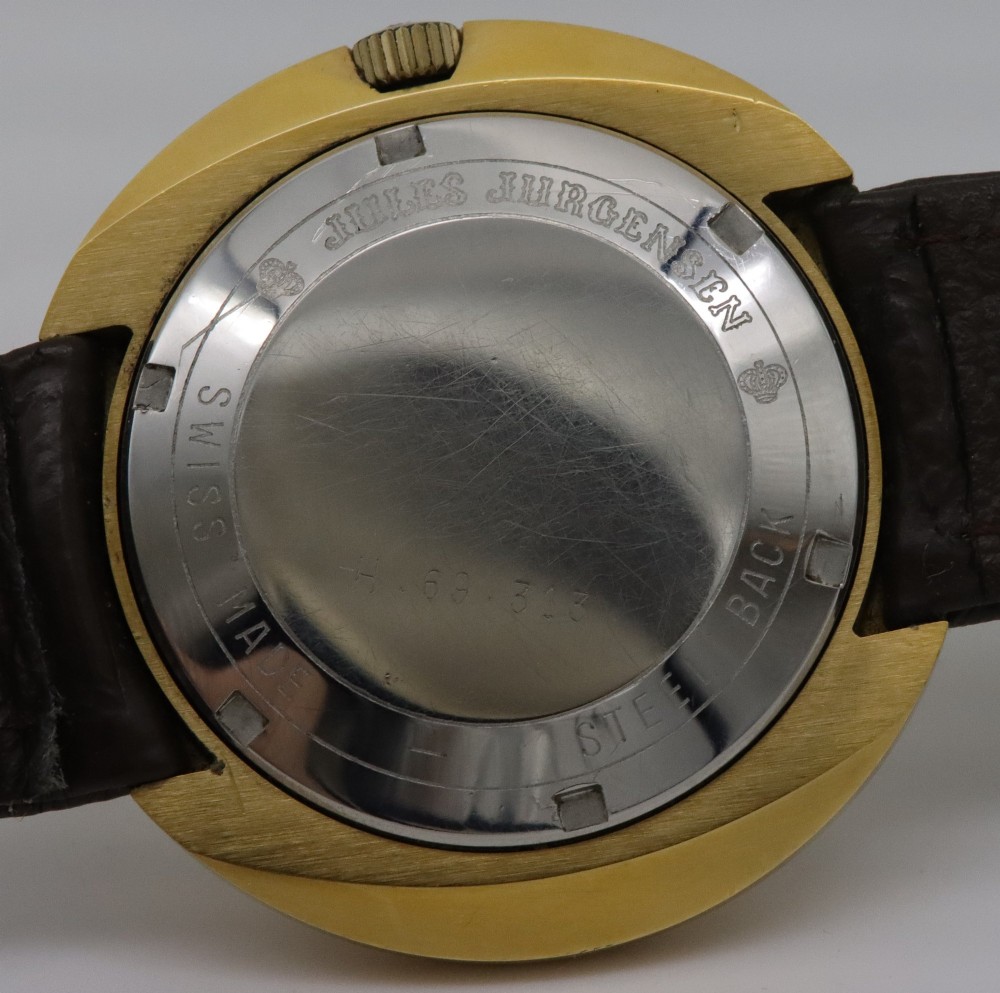 A 1970s Jules Jurgensen automatic wristwatch with a gold-toned circular cushion case, white dial, date aperture, and brown textured leather strap. View VI