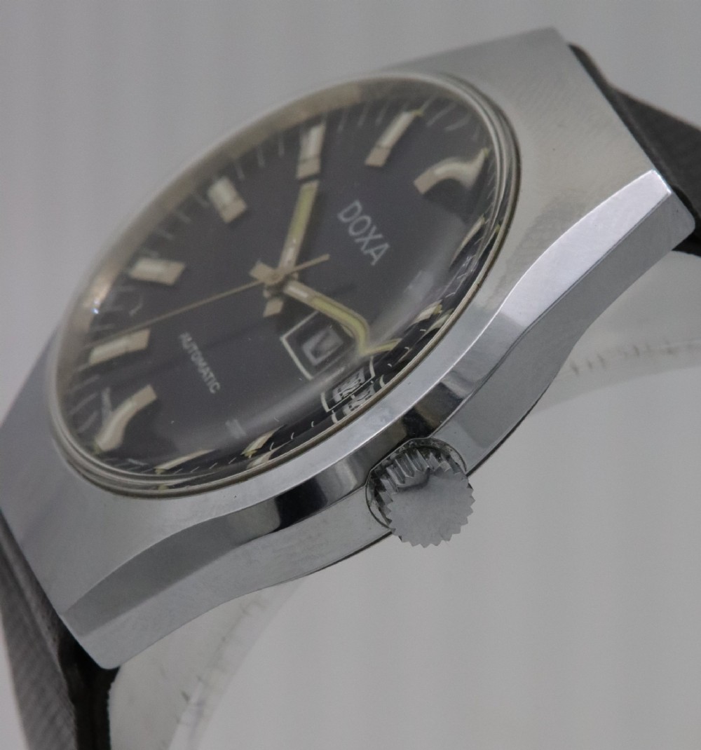 A 1970s Doxa automatic wristwatch featuring a cushion-shaped stainless steel case, blue dial with day-date aperture, and black strap. View III