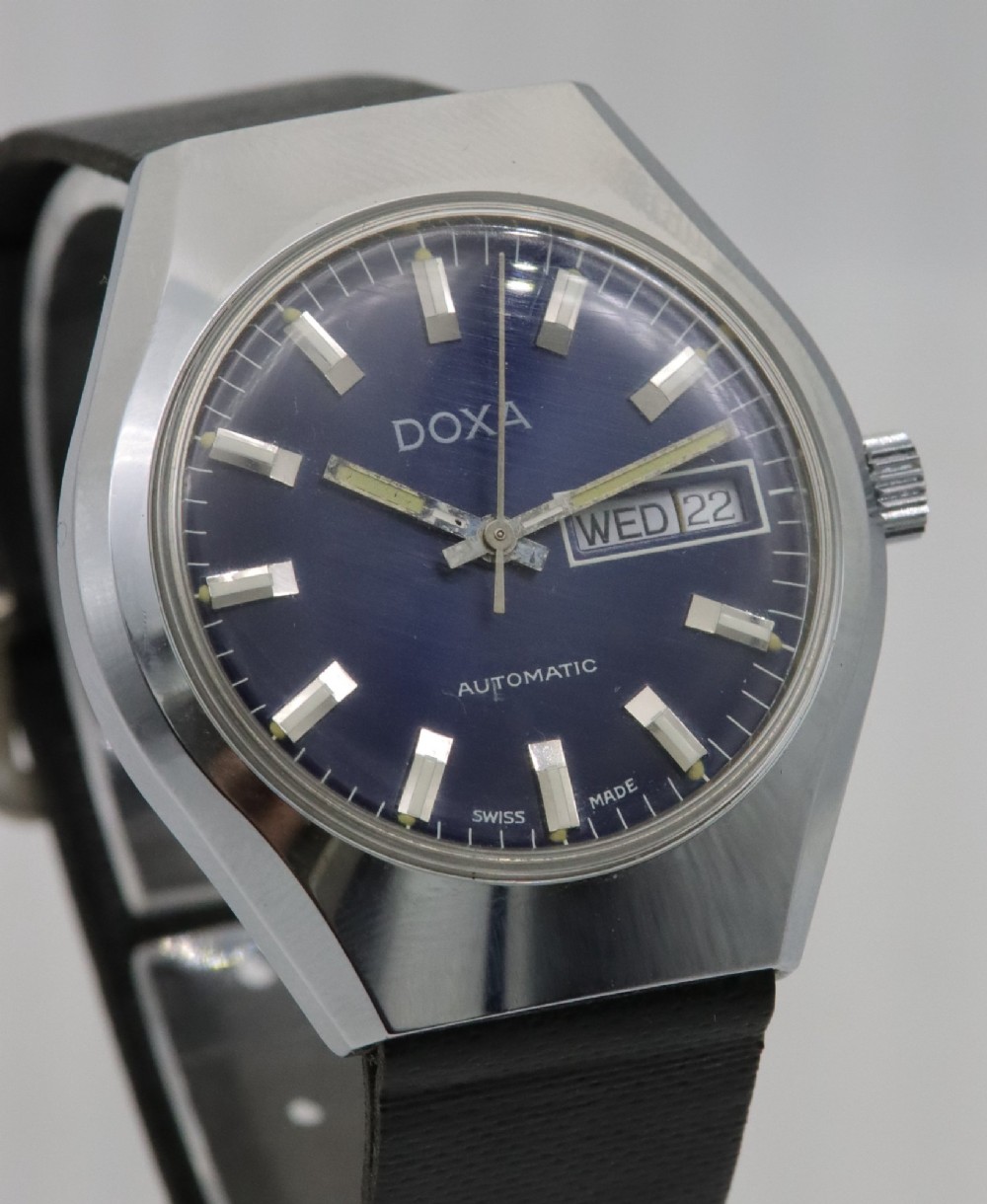 A 1970s Doxa automatic wristwatch featuring a cushion-shaped stainless steel case, blue dial with day-date aperture, and black strap. View IV