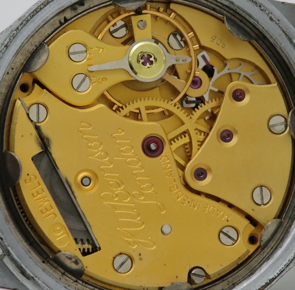 A 1950s J.W. Benson wristwatch featuring a black dial, gold-toned hands, a sub-seconds subdial at six oclock, a metallic case, and a smooth brown leather strap. View VII