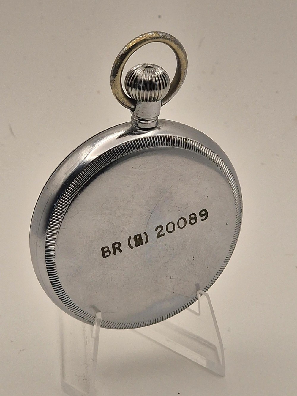 An open-face vintage pocket watch with a silver-toned metal casing, white enamel dial displaying bold black Arabic numerals, and a small sub-seconds dial. View II
