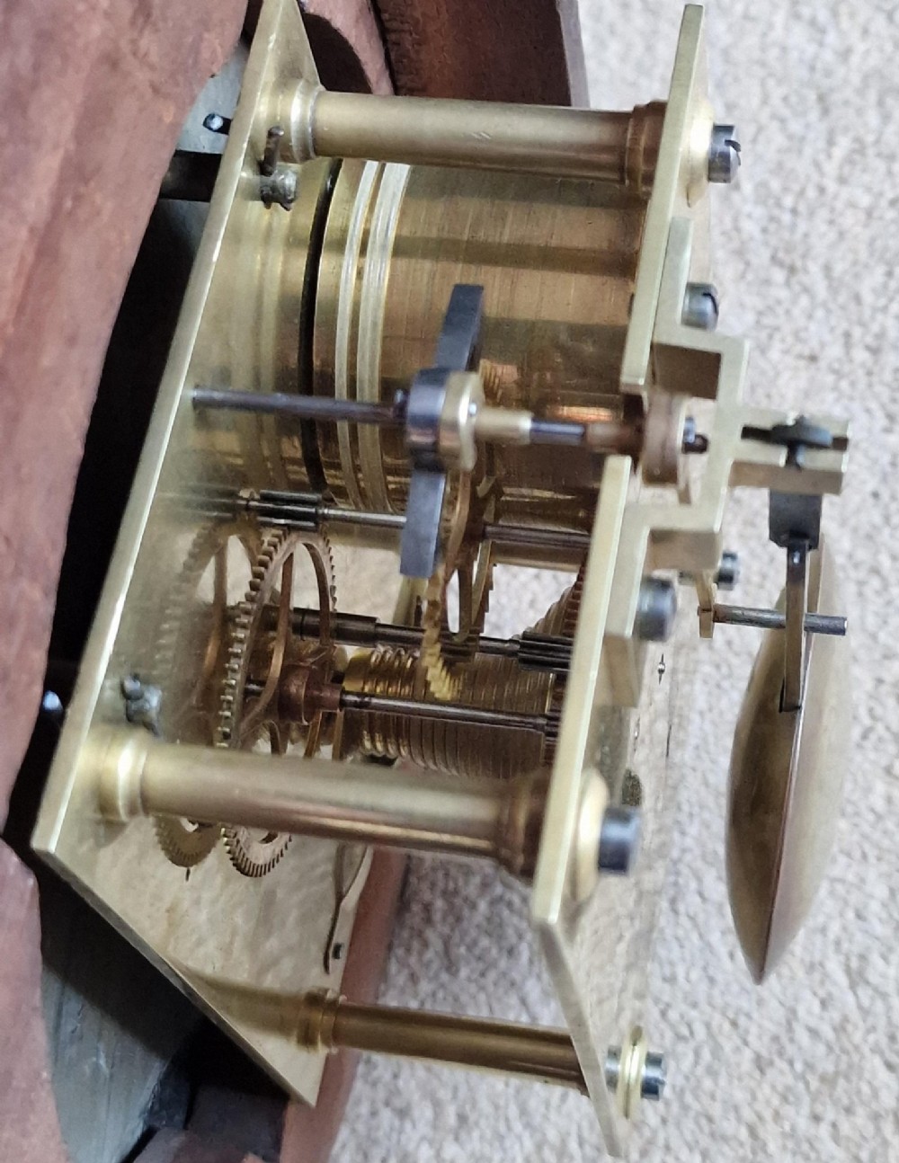A circular Victorian fusee wall clock set in a turned mahogany case with a white dial, black Roman numerals, and a brass bezel. View IV