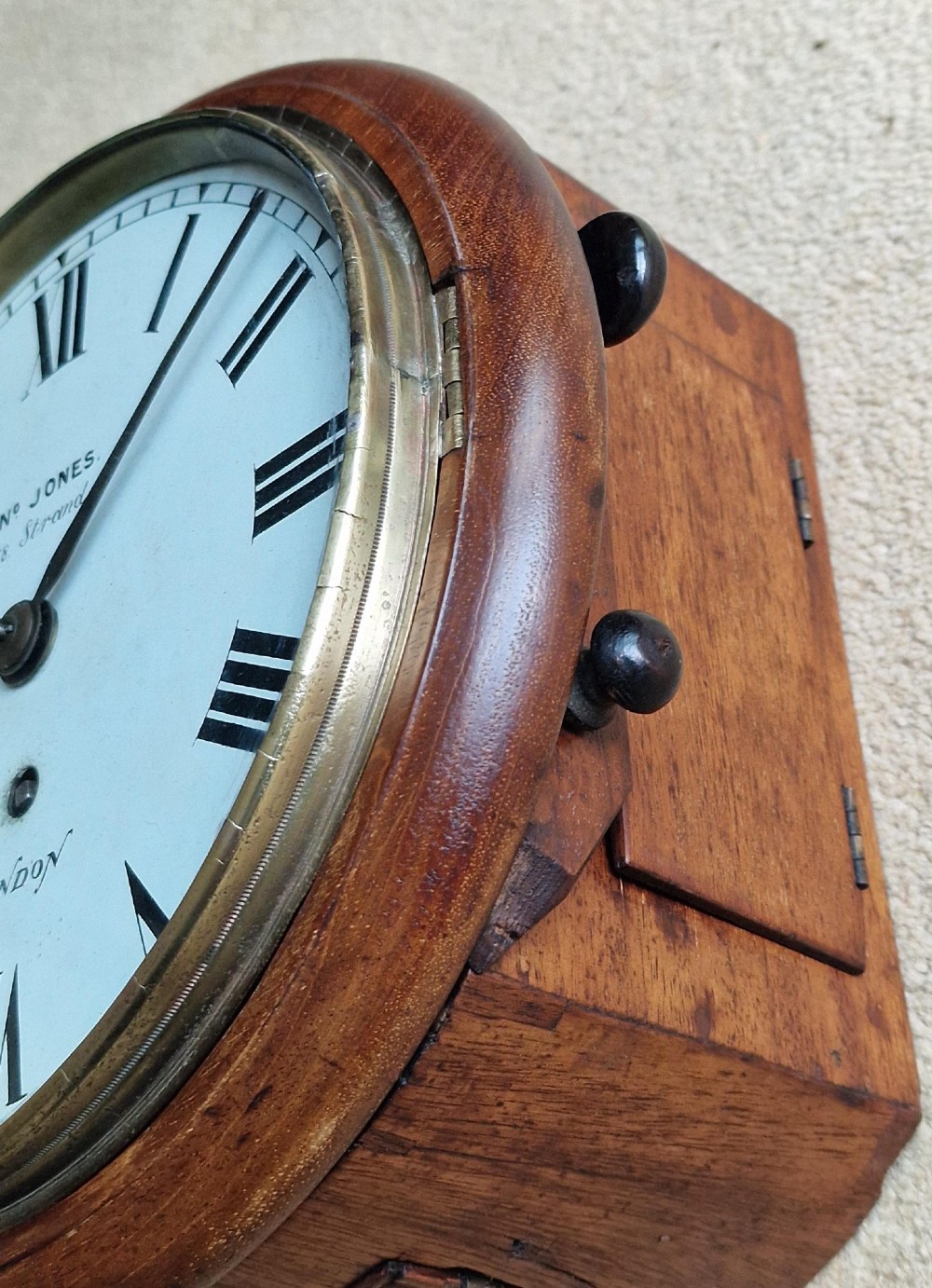 A circular Victorian fusee wall clock set in a turned mahogany case with a white dial, black Roman numerals, and a brass bezel. View V
