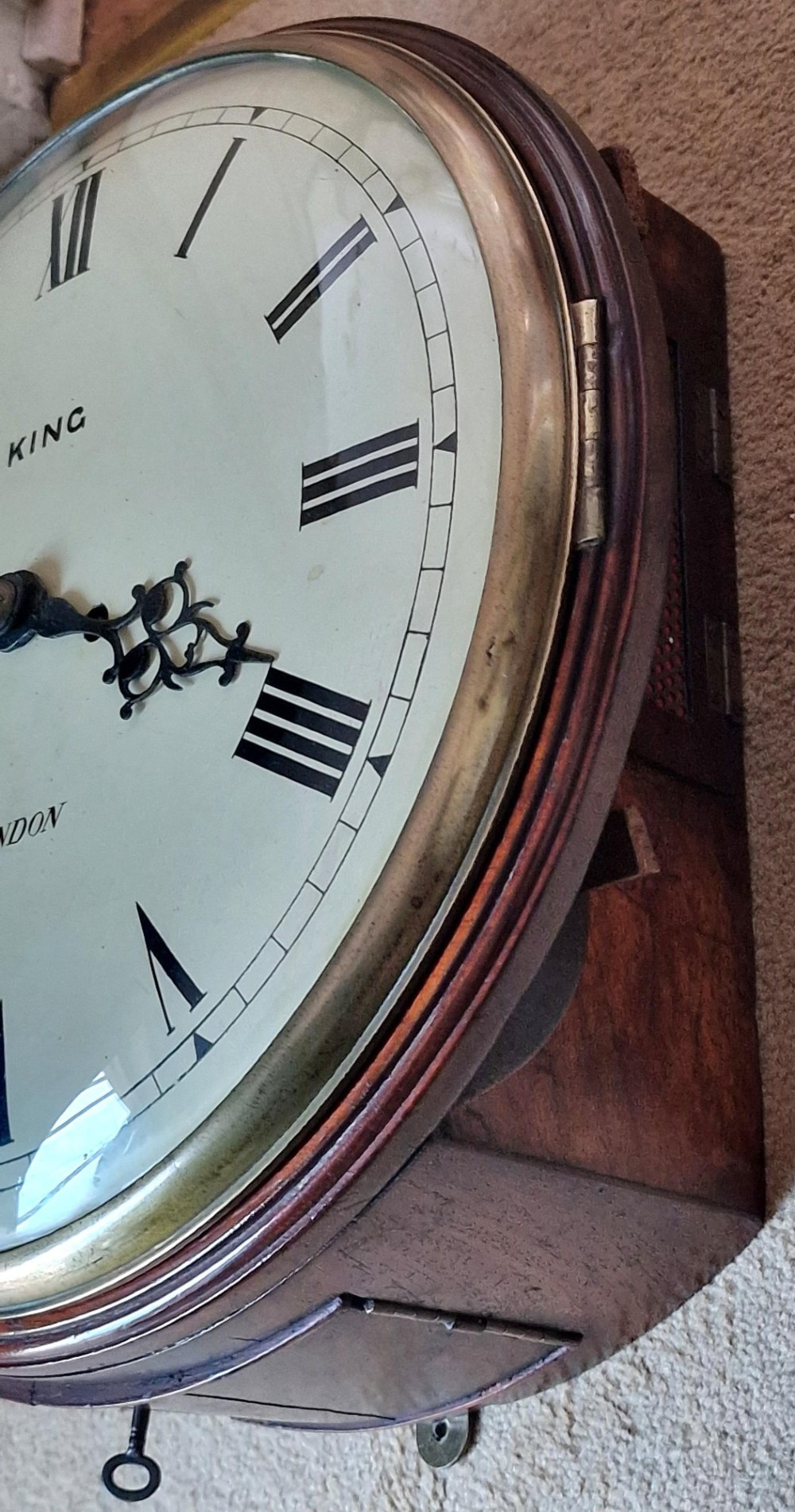 A circular Georgian fusee wall clock with a dark mahogany bezel surround, off-white painted dial featuring Roman numerals, ornate black hands, and signed King London. View IV