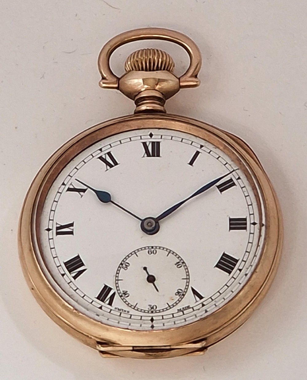 An antique gold-toned open-face pocket watch featuring a white enamel dial with black Roman numerals, blued steel hands, and a sub-seconds dial.