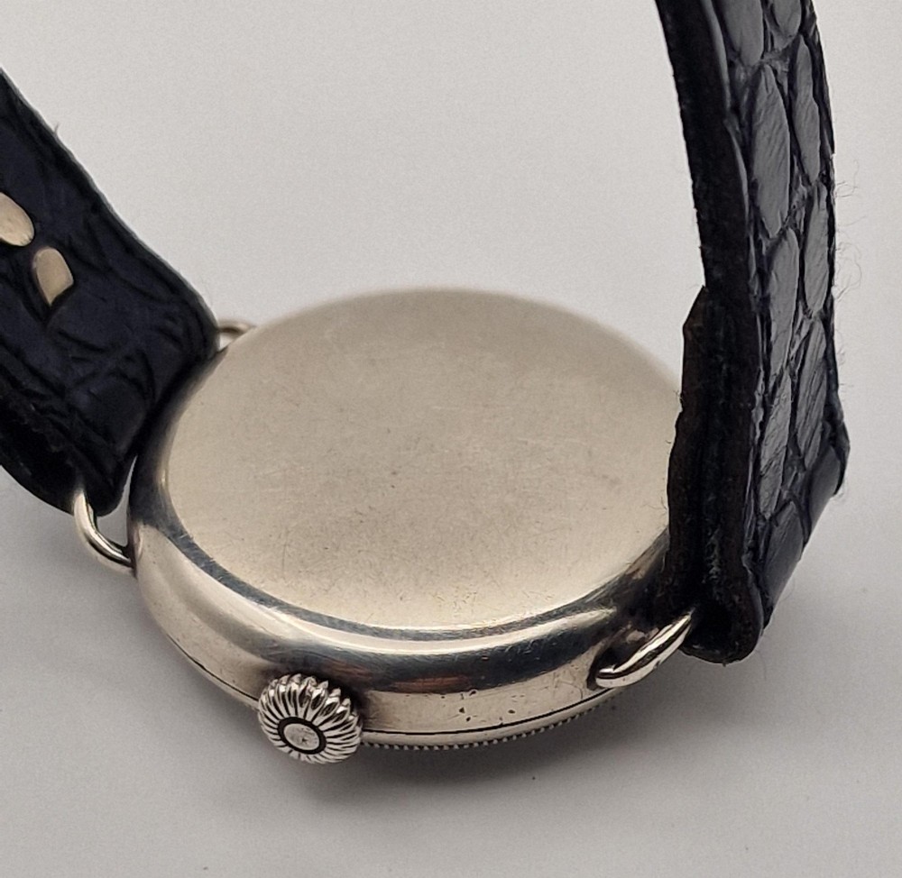 A 1934 Omega pilot wristwatch featuring a white enamel dial with Roman numerals, an offset sub-seconds dial, blued steel hands, a coin-edge bezel, and a black leather strap. View II