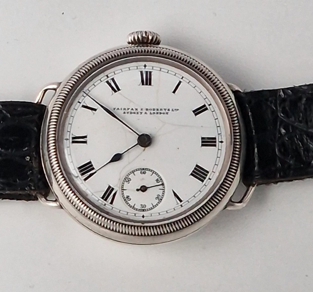 A 1934 Omega pilot wristwatch featuring a white enamel dial with Roman numerals, an offset sub-seconds dial, blued steel hands, a coin-edge bezel, and a black leather strap. View IV