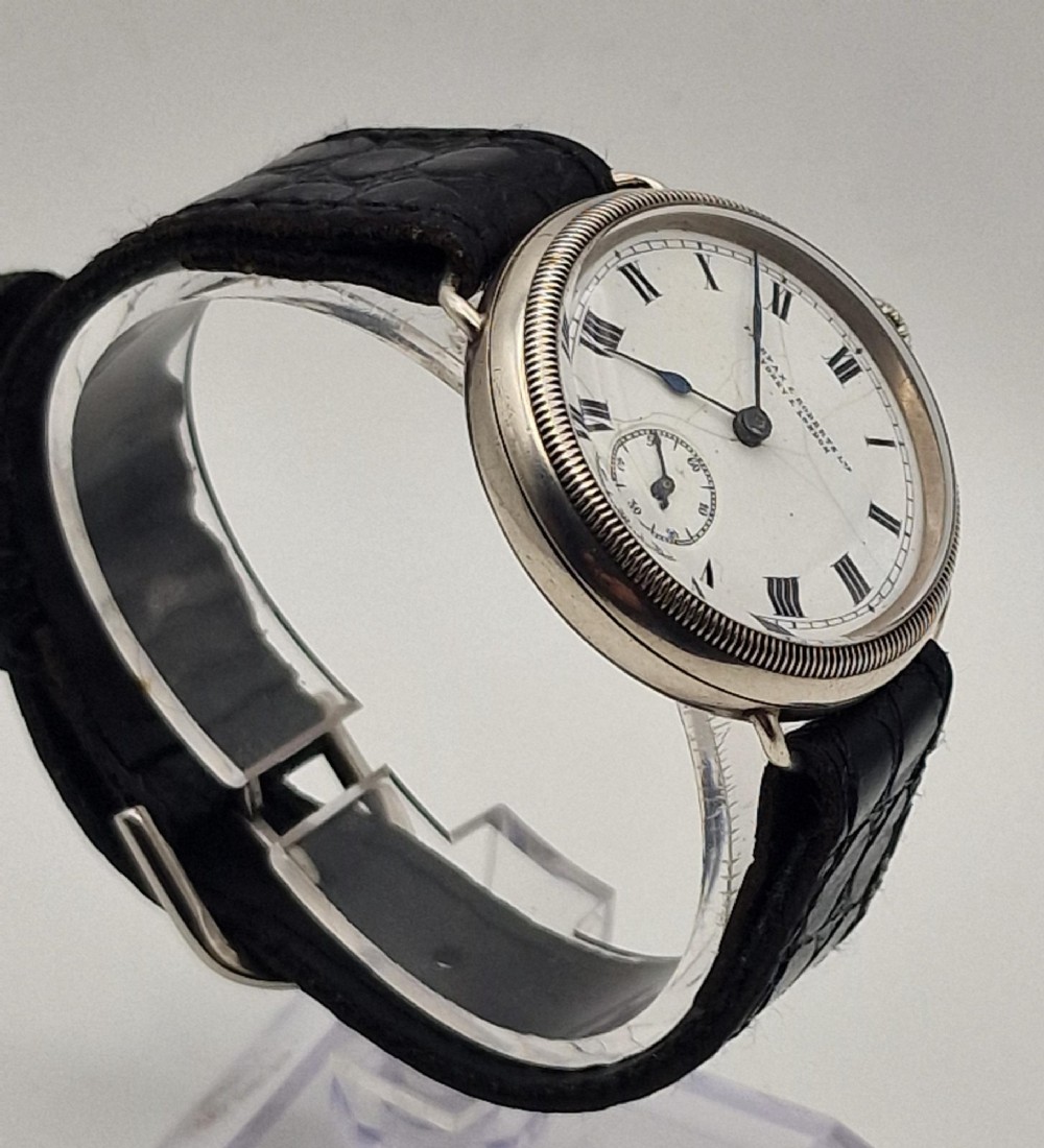 A 1934 Omega pilot wristwatch featuring a white enamel dial with Roman numerals, an offset sub-seconds dial, blued steel hands, a coin-edge bezel, and a black leather strap. View V