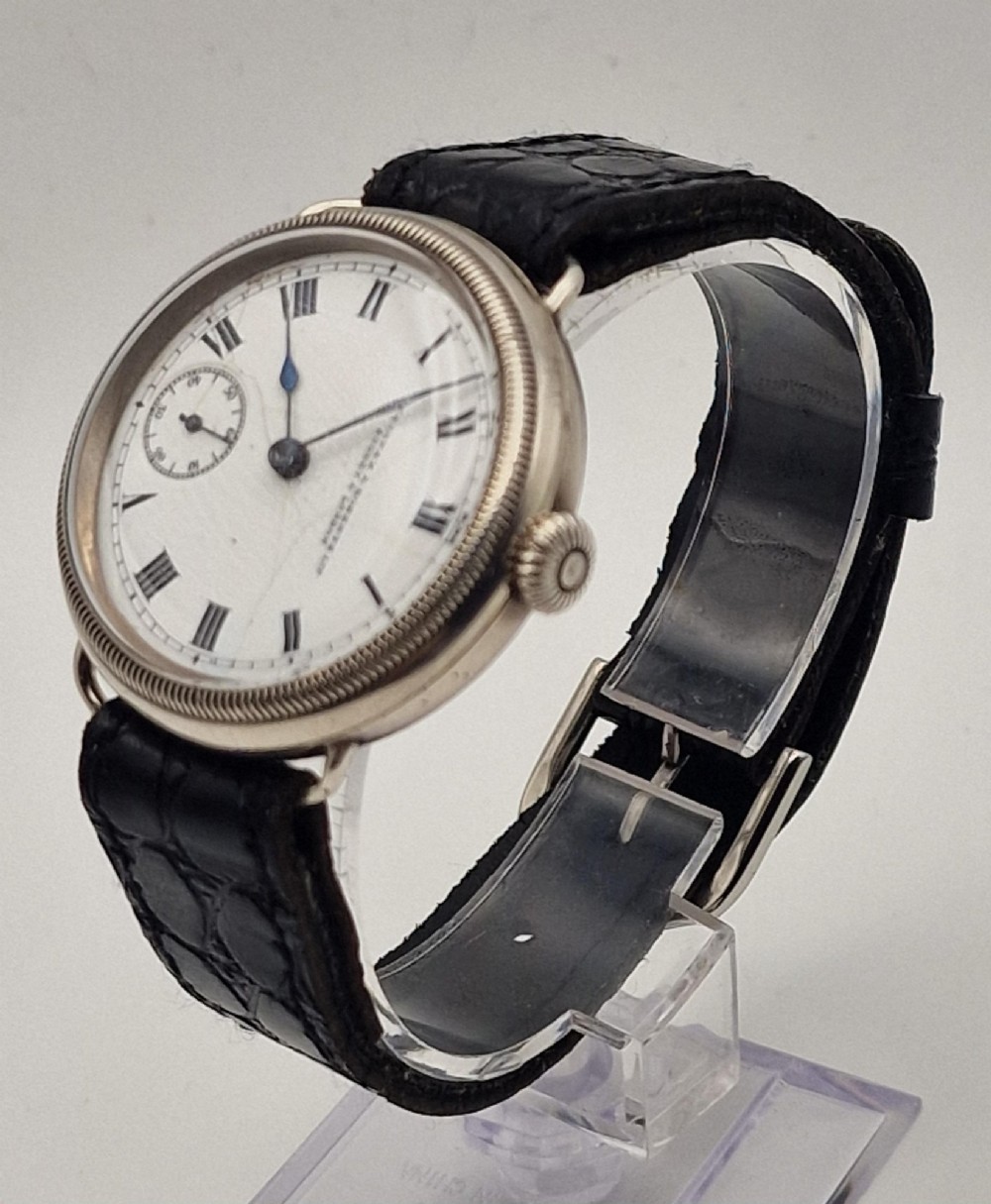 A 1934 Omega pilot wristwatch featuring a white enamel dial with Roman numerals, an offset sub-seconds dial, blued steel hands, a coin-edge bezel, and a black leather strap. View VIII