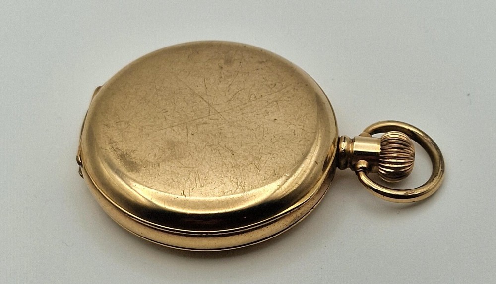 A gold-coloured half-hunter pocket watch featuring an outer case with black Roman numerals around a central glass viewing aperture. View II