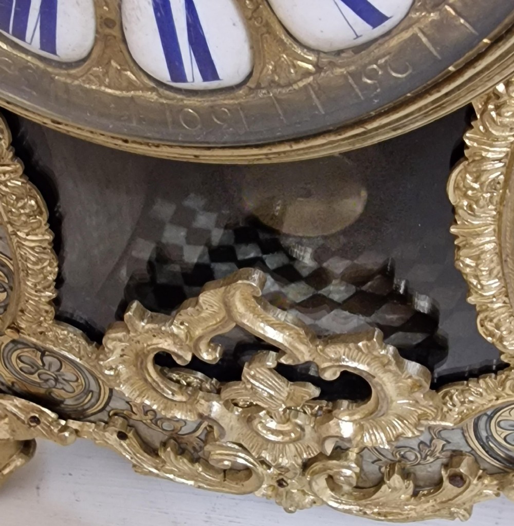 A French Rococo revival Boulle inlaid mantel clock featuring gilt brass mounts, blue Roman numerals on white enamel cartouches, and a cherub finial. View V