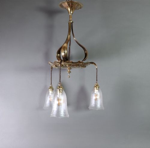 fig 2. An antique Arts and Crafts brass ceiling fixture featuring a central hand-hammered canopy and three suspended drop pendant lights with frosted bell glass shades.