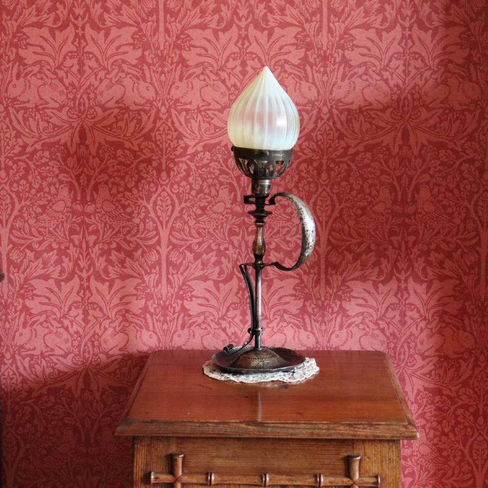 An Arts and Crafts brass table lamp featuring a hand-hammered circular base, a curved handle stem, and a flame-shaped ribbed vaseline glass shade. View III