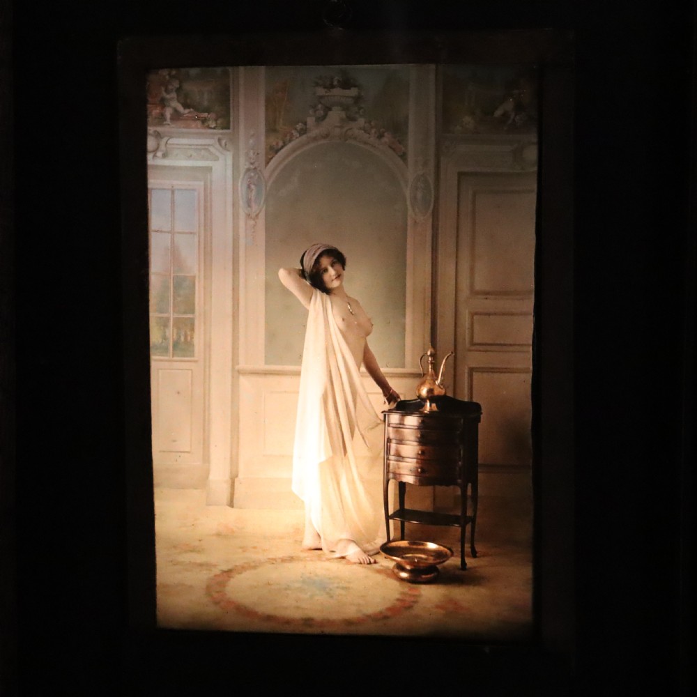 A pair of framed early glass autochrome photographs depicting female figures staged in orientalist interior settings. View III