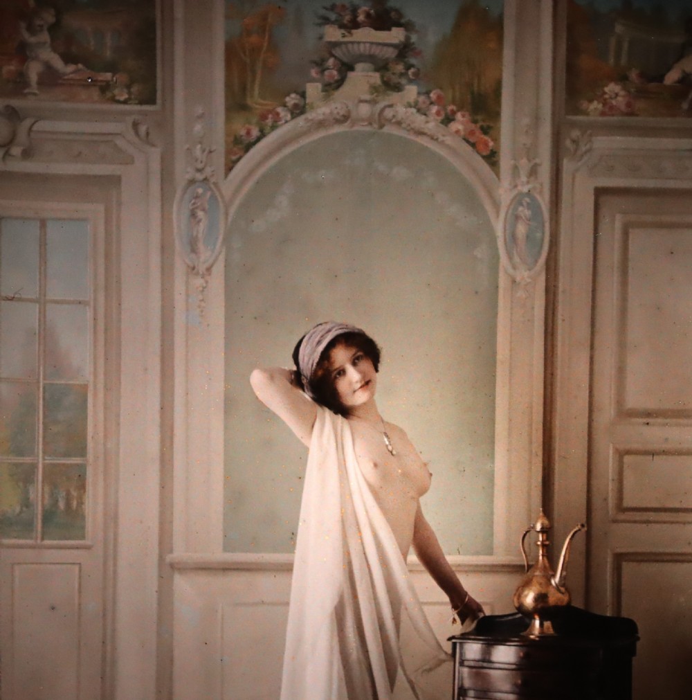 A pair of framed early glass autochrome photographs depicting female figures staged in orientalist interior settings. View IV