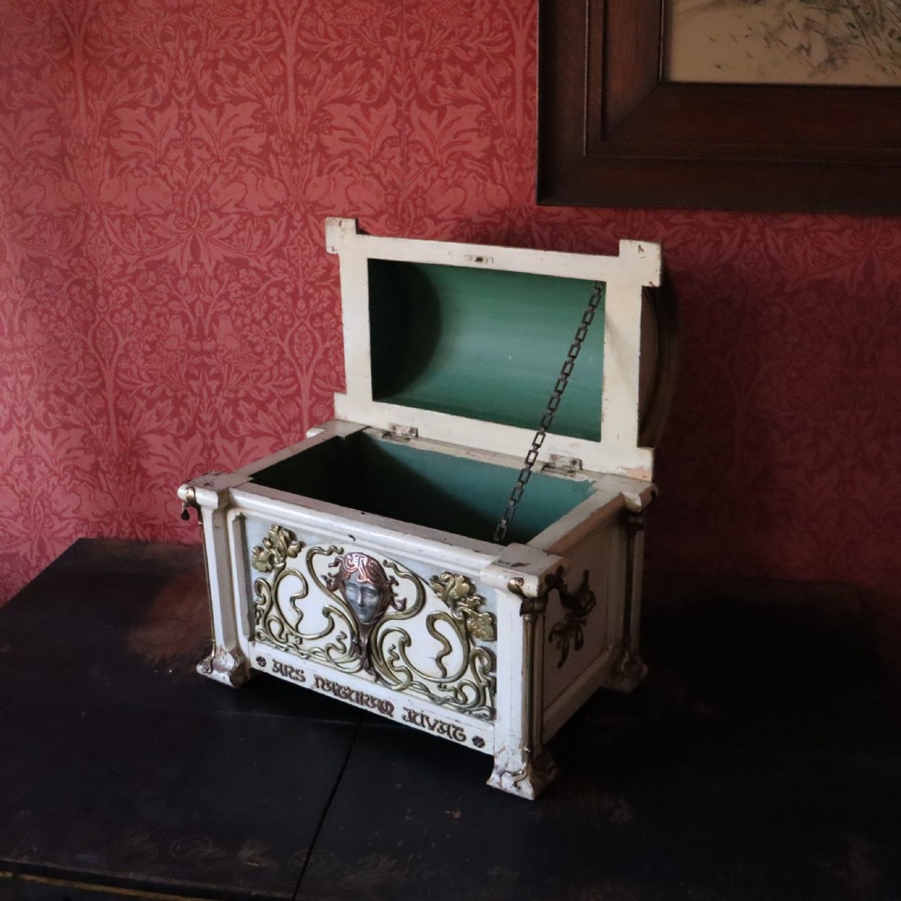 A cream-painted domed Art Nouveau casket featuring gilt metal whiplash scrollwork, a central relief mask, and a Latin inscription around the base. View II