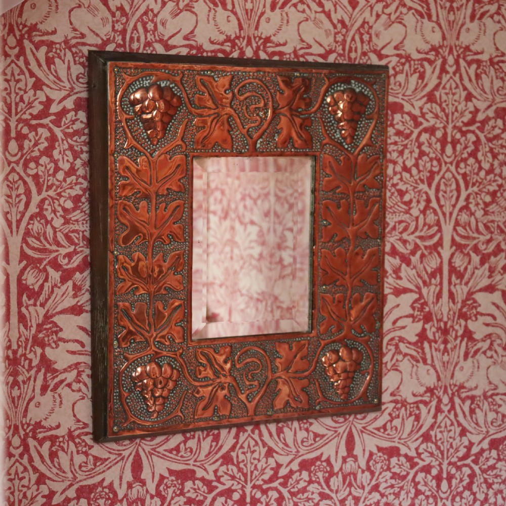 An Arts and Crafts copper repoussé wall mirror 