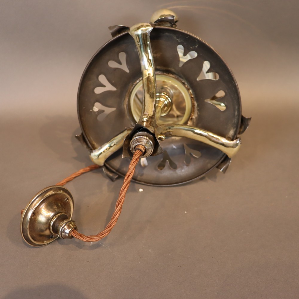 An Arts and Crafts brass ceiling light with organic botanical straps holding a white opalescent glass shade. View V