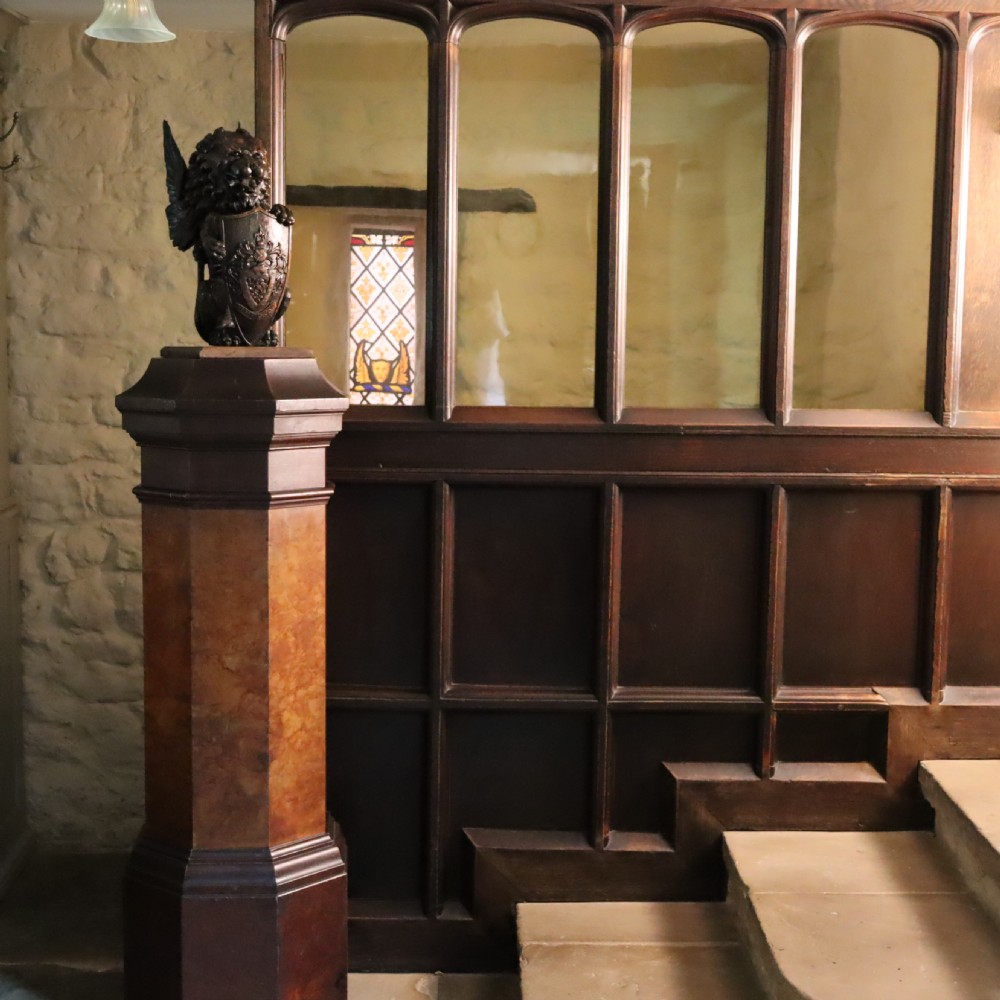 A tall octagonal Victorian column featuring a hand-painted faux marble shaft in warm ochre tones supported by a dark brown octagonal base and capital. View VII