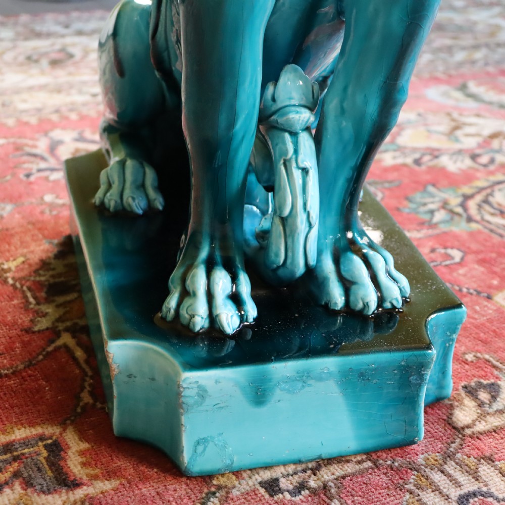A bright turquoise glazed ceramic jardiniere with lion head swags resting on a matching winged griffin pedestal stand. View VIII