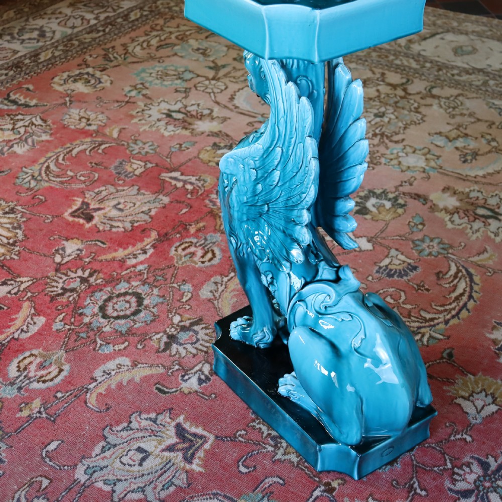 A bright turquoise glazed ceramic jardiniere with lion head swags resting on a matching winged griffin pedestal stand. View IX