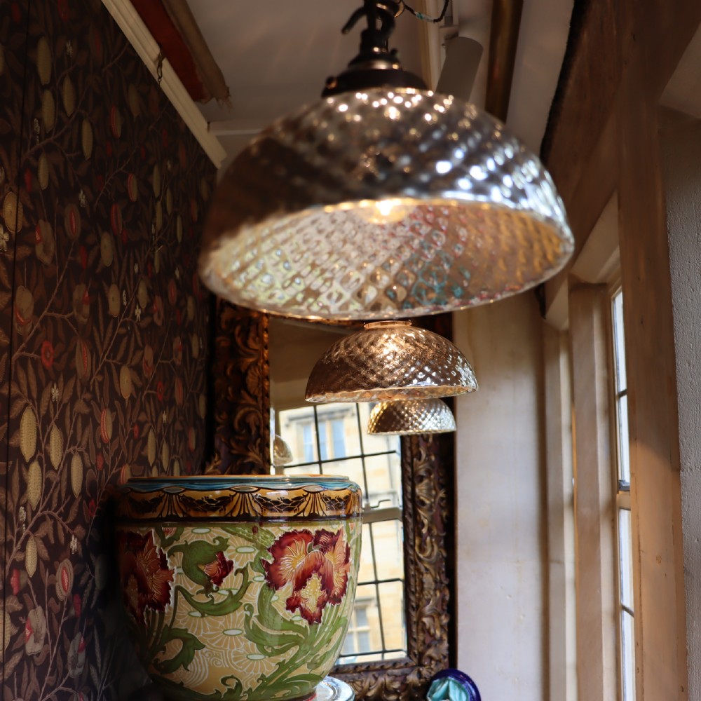 A dome-shaped mercury glass pendant light shade with a dappled silvered interior finish and aged brass fittings. View V