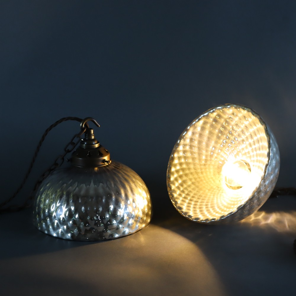 A pair of circa 1920 mercury glass pendant lights featuring textured silvered shades and dark brass galleries with hanging hooks. View II