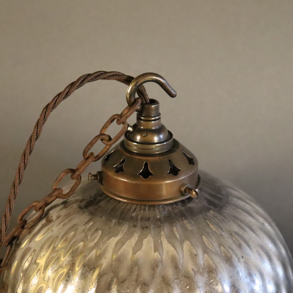 A pair of circa 1920 mercury glass pendant lights featuring textured silvered shades and dark brass galleries with hanging hooks. View IV