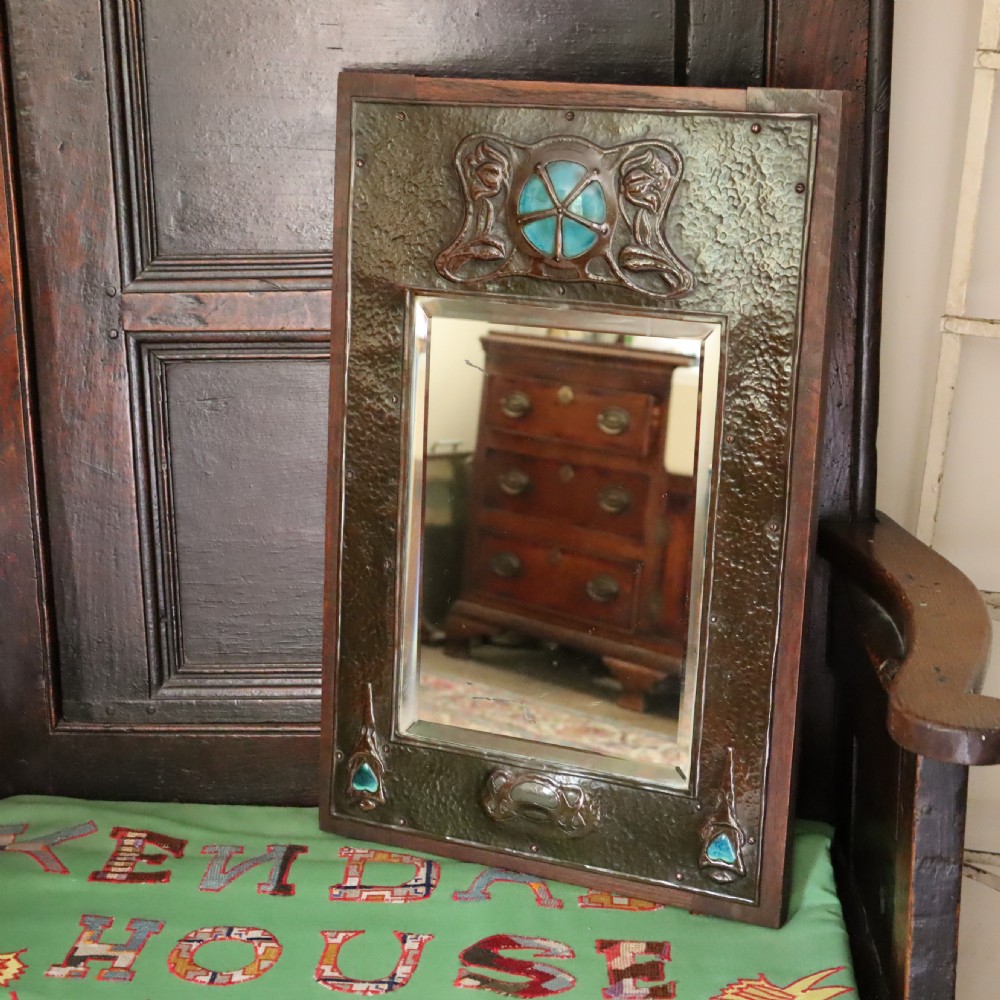 An Arts and Crafts repoussé and oak framed mirror. View II