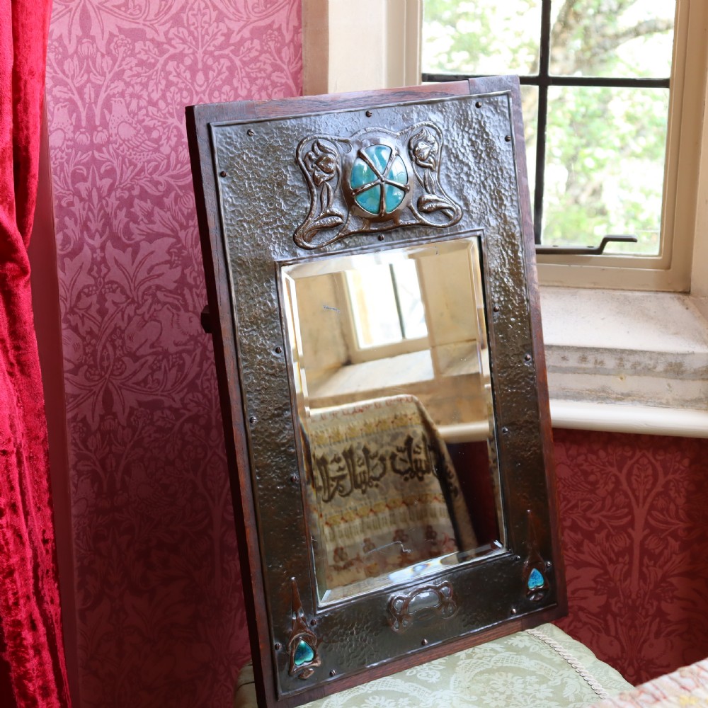 An Arts and Crafts repoussé and oak framed mirror. View III