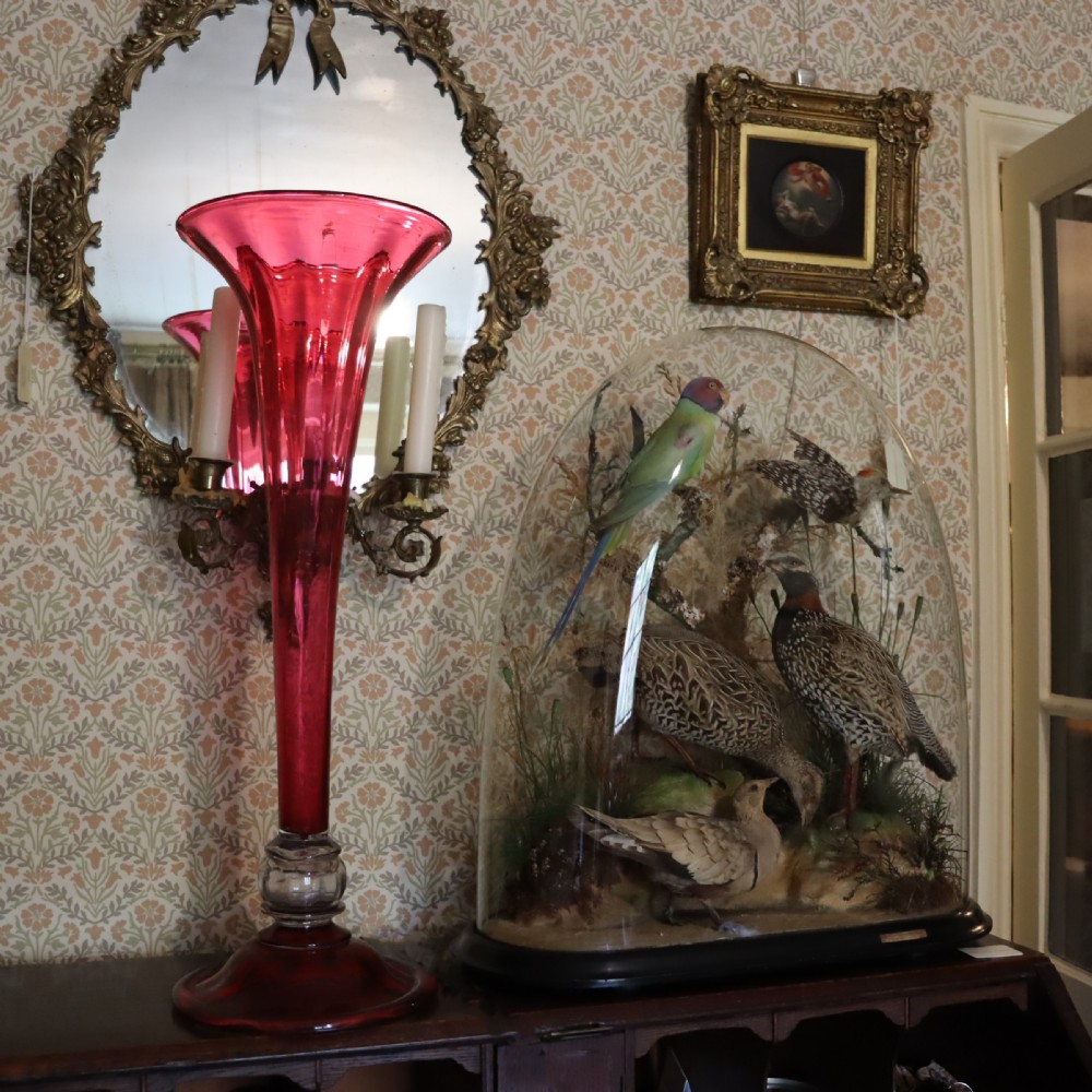 A tall Victorian trumpet-shaped vase made of deep red cranberry glass with a clear glass knop and circular foot. View II