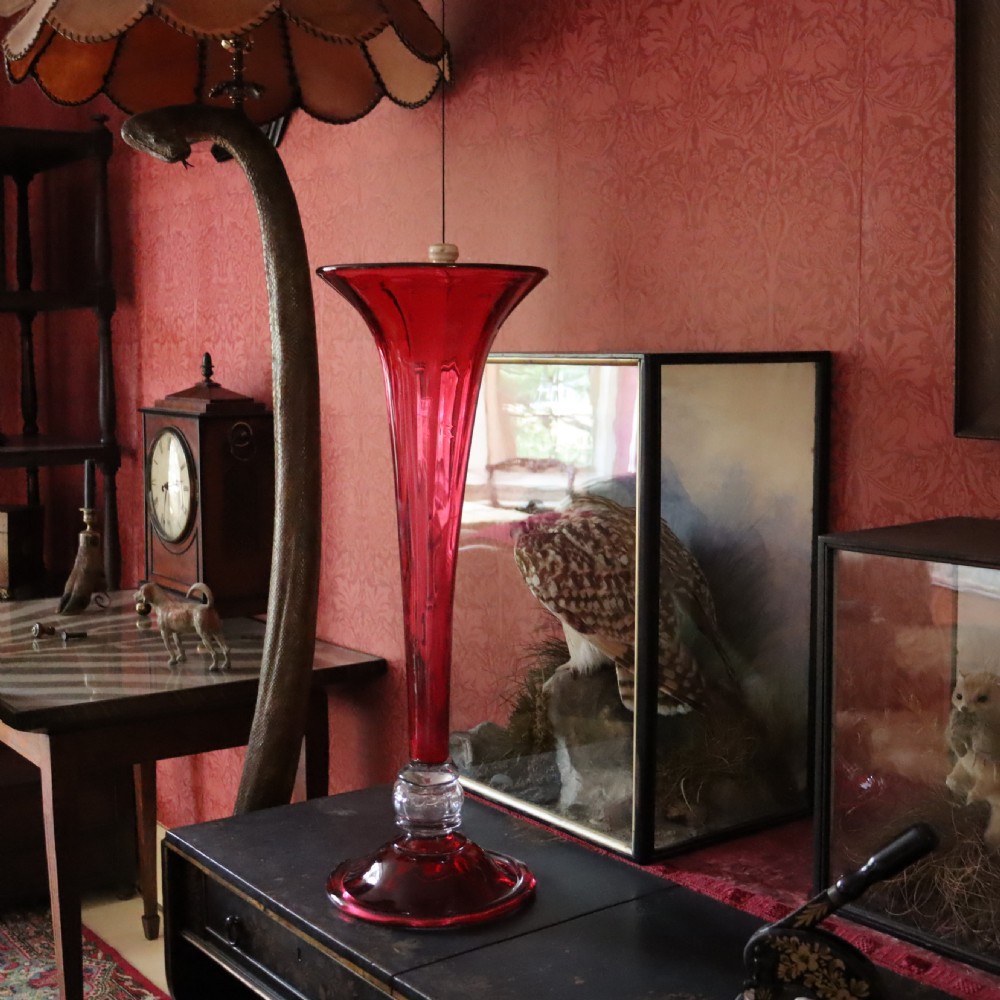 A tall Victorian trumpet-shaped vase made of deep red cranberry glass with a clear glass knop and circular foot. View III