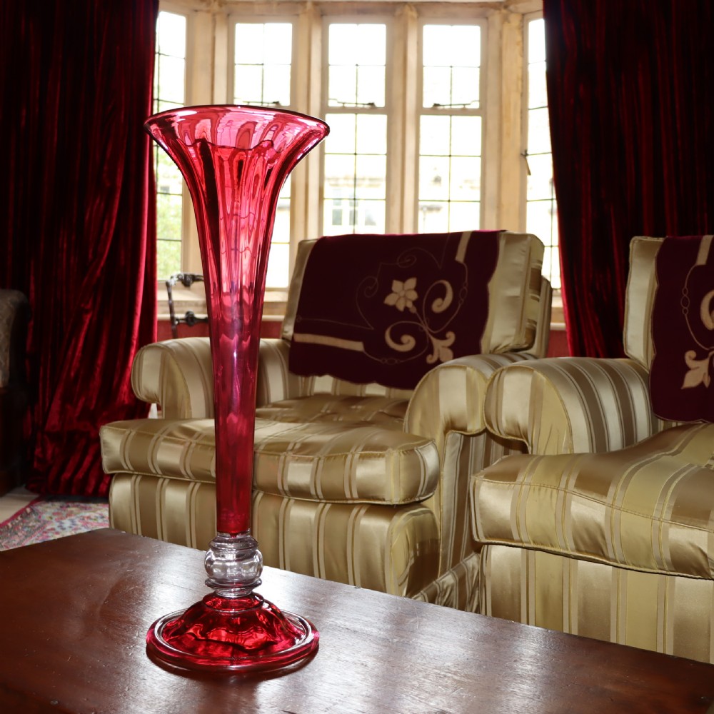 A tall Victorian trumpet-shaped vase made of deep red cranberry glass with a clear glass knop and circular foot. View V