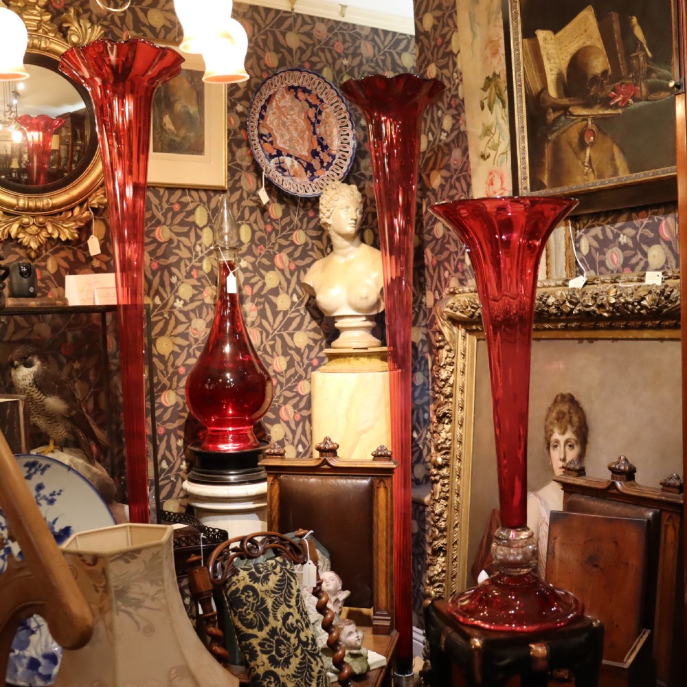 A tall Victorian trumpet-shaped vase made of deep red cranberry glass with a clear glass knop and circular foot. View VIII