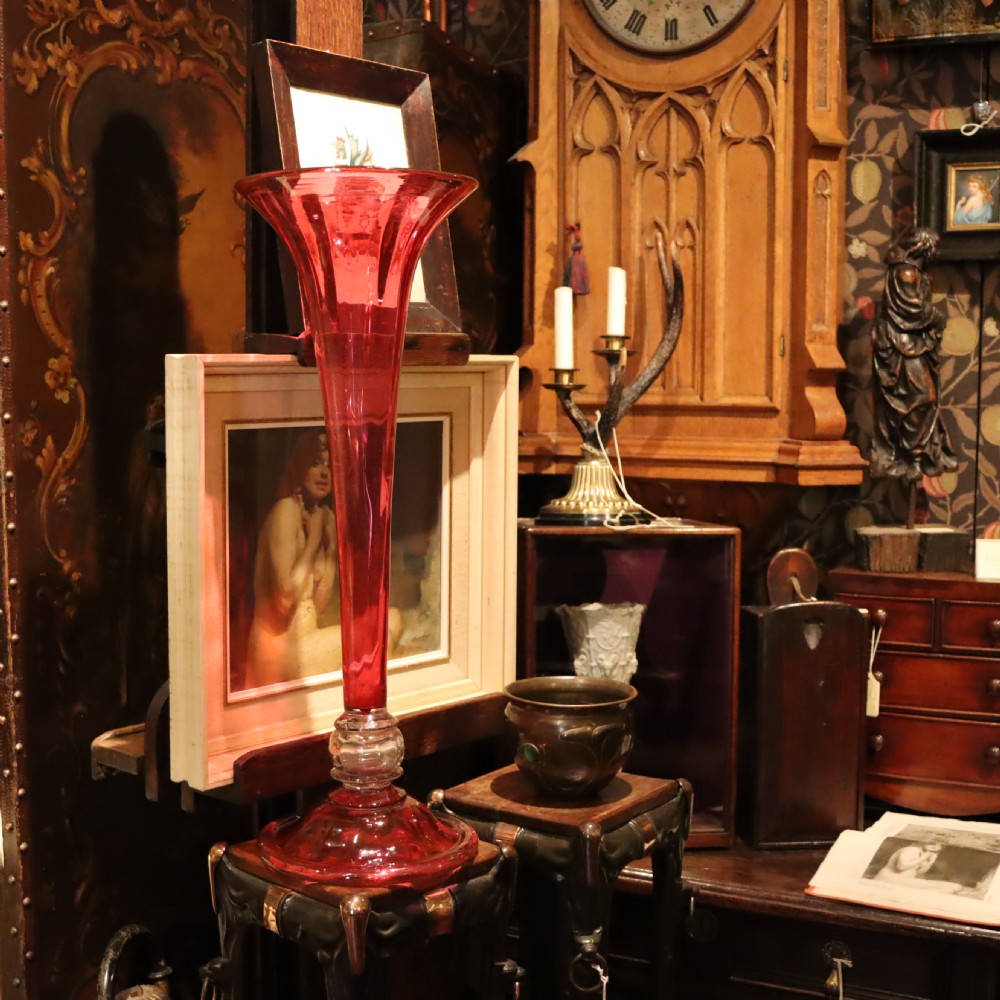 A tall Victorian trumpet-shaped vase made of deep red cranberry glass with a clear glass knop and circular foot. View IX