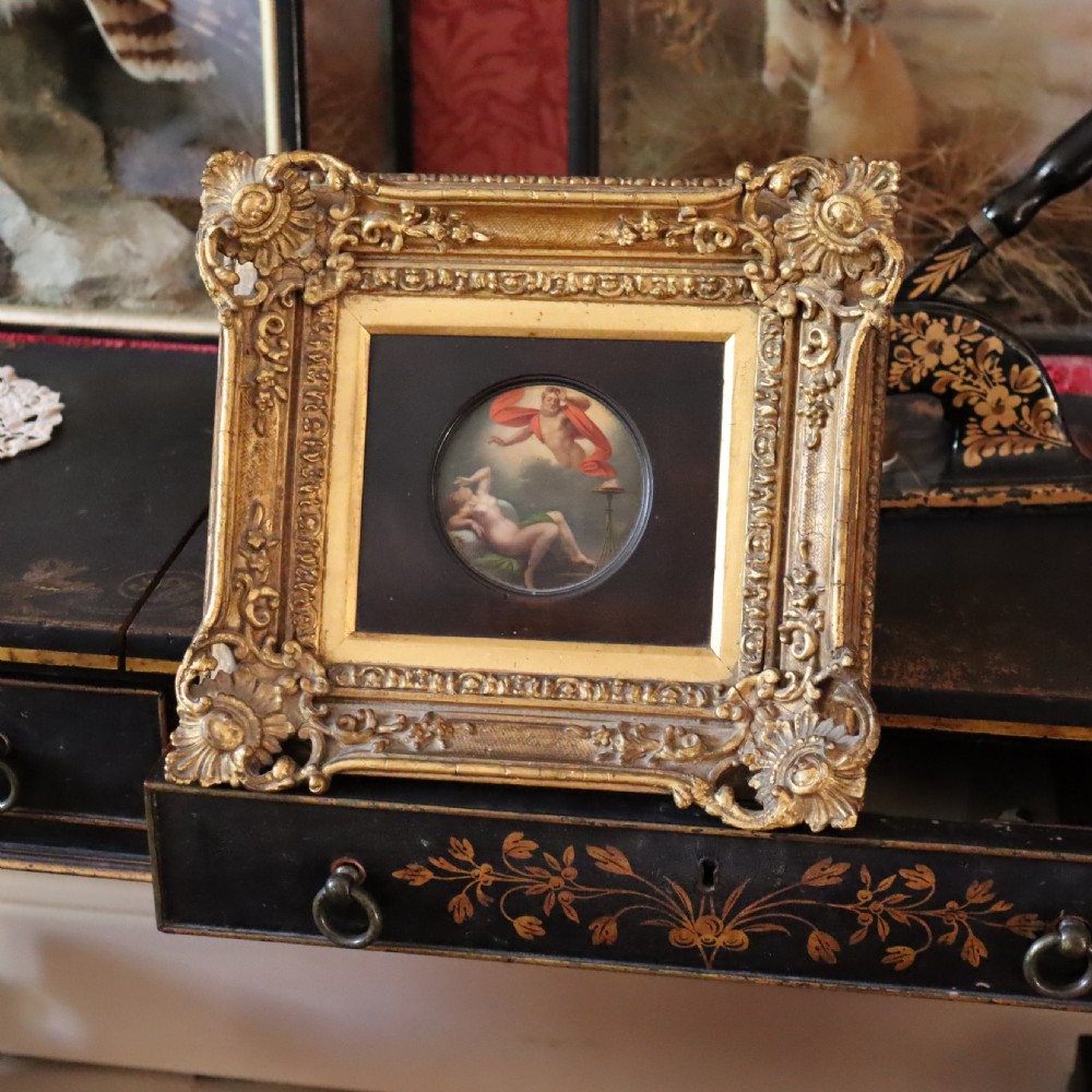 A small circular early 19th-century mythological oil painting depicting a reclining nude nymph and floating male god, encased in a square, highly ornate giltwood frame. View VIII