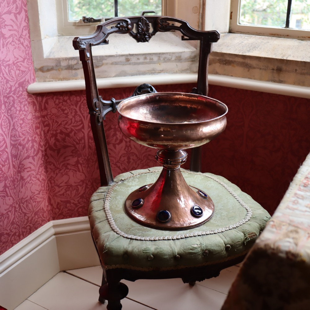 A hand-hammered copper pedestal bowl featuring a flared base set with circular blue enamel cabochons. View II