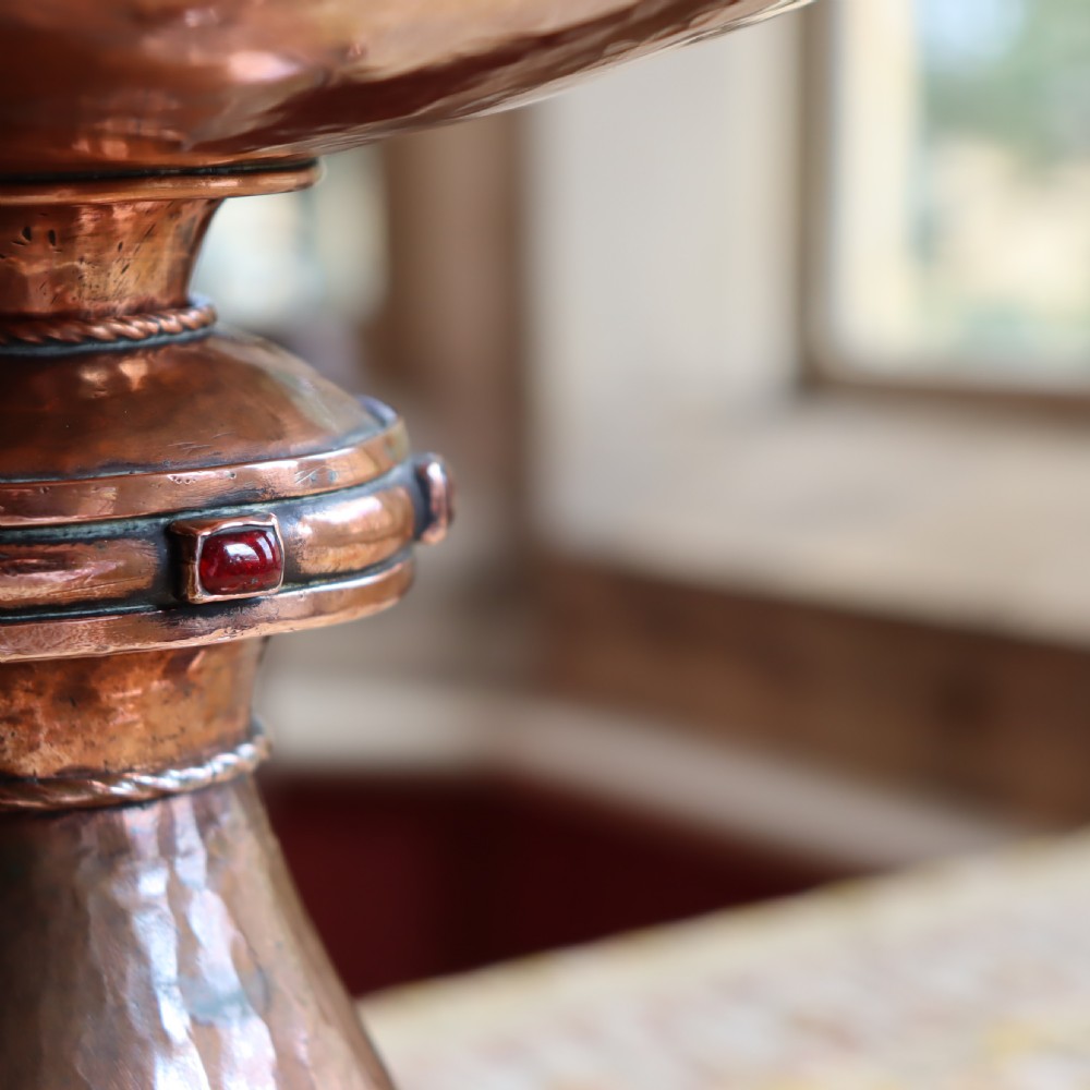 A hand-hammered copper pedestal bowl featuring a flared base set with circular blue enamel cabochons. View VI