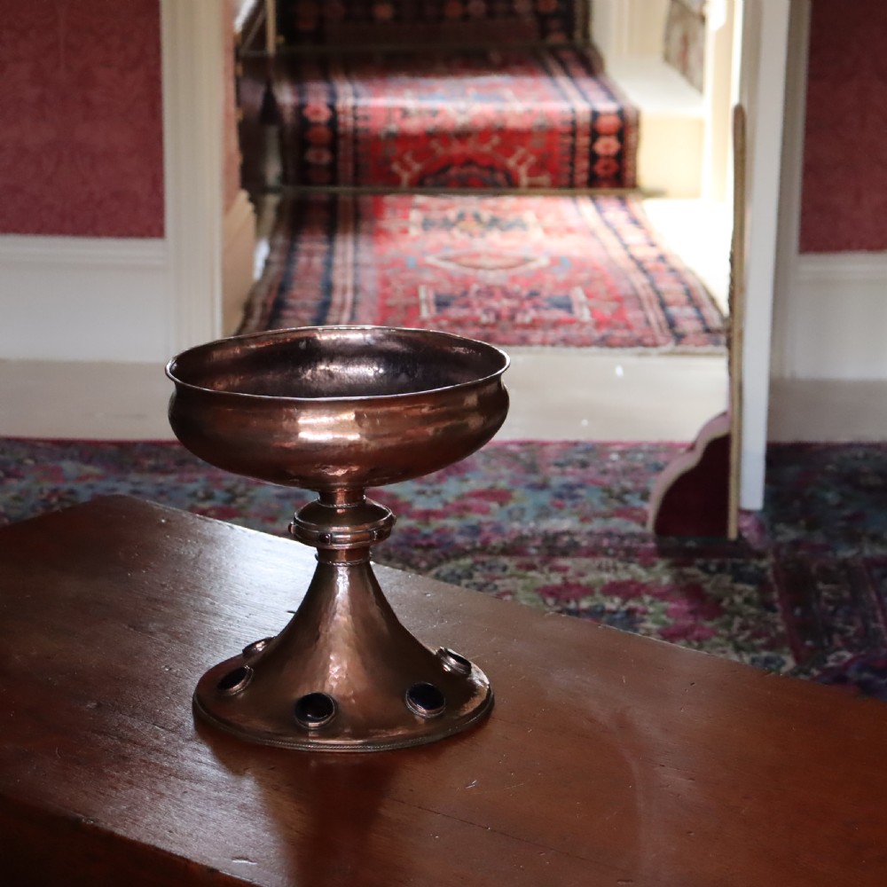 A hand-hammered copper pedestal bowl featuring a flared base set with circular blue enamel cabochons. View VII