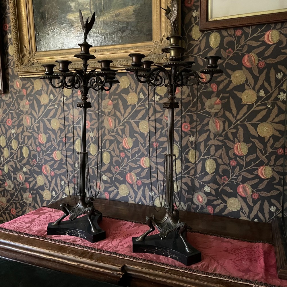 A pair of dark bronze Neoclassical candelabra featuring scrolling branches, bird finials, hanging chains, and black marble bases.