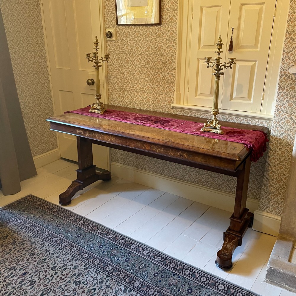 A Late Regency rectangular rosewood library table featuring inlaid floral marquetry along the frieze and pedestal supports.